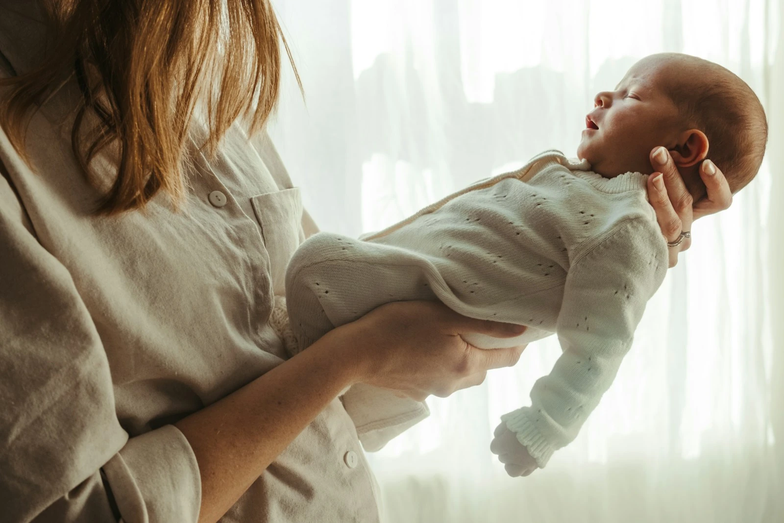 Mother holding her newborn baby near a sunlit window